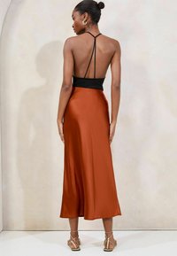 Satin midi Kleita ar melnu augšu un spilgtu rūsas krāsas svārku, ar plānām siksnām un zemu muguras dizainu.