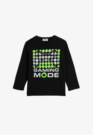 Camiseta negra de manga larga con un diseño gráfico que presenta círculos verdes y grises, el texto "MODO JUEGO" y un icono de botón de encendido.