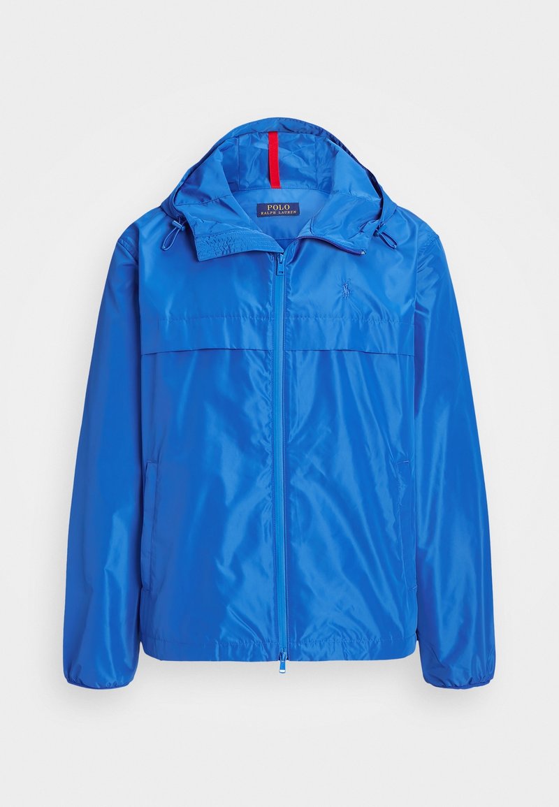 Chaqueta ligera azul con cierre de cremallera en la parte delantera, capucha ajustable y dos bolsillos laterales. Presenta una textura suave y brillante y un detalle de logo en el pecho.