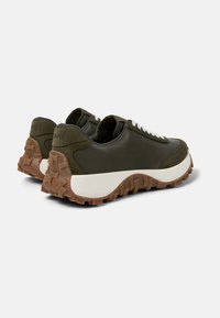 Sneaker in pelle verde e suède con una spessa intersuola bianca e una suola in gomma marrone testurizzata. Presenta un loop posteriore e lacci bianchi.