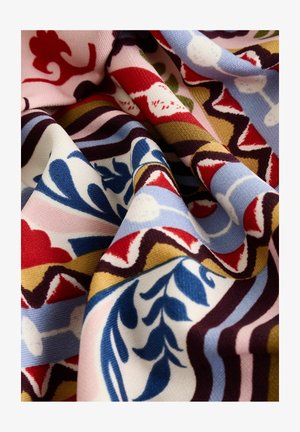 Kangas kangastootes, millel on keerukad lillemustrid punases, sinises, rohelises ja roosas kooskõlas kreemika taustaga ning tekstuurse kudumisega.