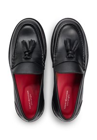 Μαύρα δερμάτινα μοκασίνια με ανάγλυφο σχέδιο ραφής, διπλές φούντες και κόκκινους πάτους με το λογότυπο της μάρκας.