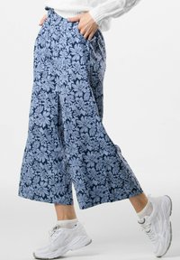 Blommönstrade byxor i marinblått med ljusblå blommor. Vid ben-design, elastisk midja, sidofickor, i kombination med vita sneakers.