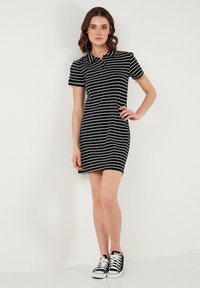 Rö stripes musta ja valge polo kleit lühikeste varrukatega, sirge lõikega ja kraega. Sobib mustade ja valgete spordijalatsitega. Sile kangas.