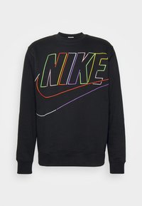 Juodas džemperis su dideliu, daugiaspalviu "NIKE" logotipu ir swoosh dizainu priekyje. Pagamintas iš minkštos, tekstūruotos medžiagos.