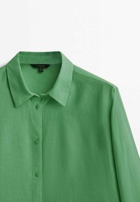 Green button-up shirt with collar and long sleeves, made of lightweight fabric, shown against a white background.