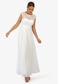 Maxi sukienka w kolorze białym z koronkowym gorsetem w kwiaty, rękawami typu cap oraz zwiewną spódnicą z szyfonu. Prosty, elegancki fason z naturalną talią.