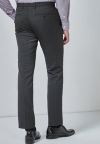 Graue maßgeschneiderte Hose aus glattem Material, mit zwei Gesäßtaschen mit Knöpfen, schlanker Schnitt und flacher Vorderseite.