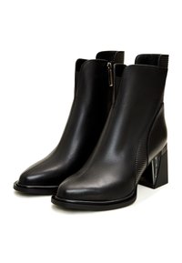 Bottines noires en cuir avec un design épuré, bout pointu et un panneau latéral texturé. Le talon carré transparent ajoute du contraste.