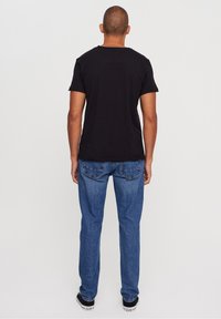 Svart bomulls t-shirt med kort ärm, kombinerad med blå denimjeans med en klassisk femficksdesign och rak passform.