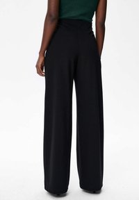 Zwarte broek met wijde pijpen en een hoge taille, gemaakt van een gladde stof. Heeft een schone, minimalistische uitstraling zonder zichtbare zakken of accenten.