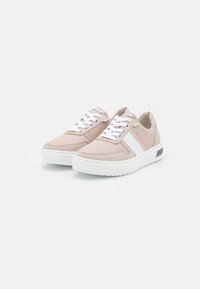 Light beige sneakers with a textured fabric upper, white laces, and a white sole; features a side stripe and a small metallic accent.