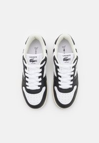 Paire de baskets Lacoste noires et blanches avec lacets, bouts perforés et logo crocodile sur la languette, vue de dessus.