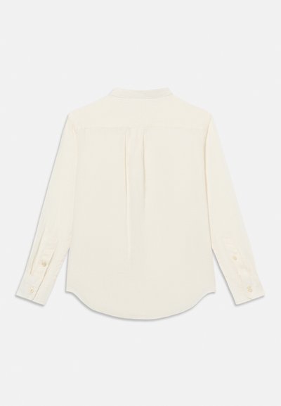 Μπλούζα κρεμ με μακριά μανίκια, μανσέτες με κουμπιά και πιέτα στην πίσω «καβάλα», απλωμένη επίπεδη σε λευκό φόντο.