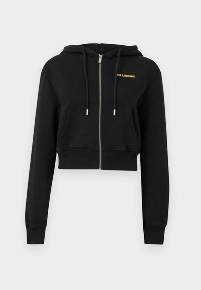 Μαύρο cropped φούτερ με φερμουάρ, μπροστινές τσέπες, κορδόνια και μικρό κίτρινο κείμενο "HAN KJØBENHAVN" στο αριστερό στήθος.
