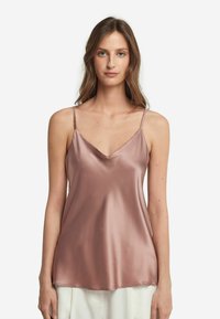 Ljusrosa satin camisole med tunna axelband, med V-ringning och en mjuk, flödande textur. Rak fåll vid midjan.