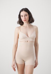 Bežový body s nastaviteľnými ramienkami, s V-krkom a vysokým pásom šortiek, vyrobený z hladkého, elastického materiálu.