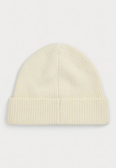 Adīta beanie mīkstā krēmkrāsā, ar ribotu tekstūru un salocītu maliņu. Augšdaļa ir noapaļota ar gludu apdari.
