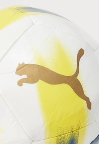 Piłka nożna PUMA, wykonana z białego materiału syntetycznego z żółtym gradientem i niebieskimi akcentami, z wyraźnym złotym logo PUMA. Teksturowana powierzchnia.