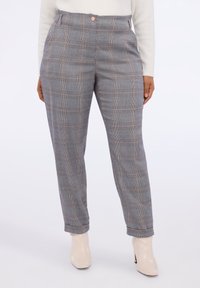 Pantalones de cuadros grises con cintura alta, que presentan un dobladillo enrollado, cierre de botón y una textura suave. Llevados con botines beige.