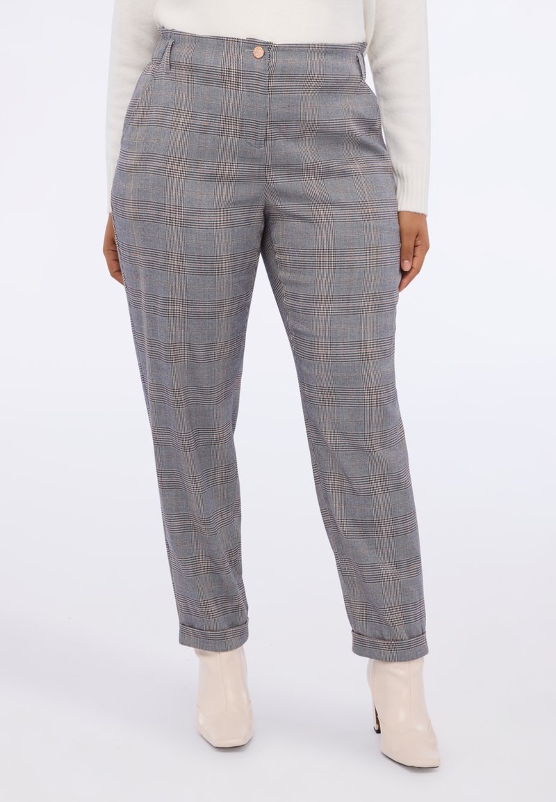 Pantalones de cuadros grises con cintura alta, que presentan un dobladillo enrollado, cierre de botón y una textura suave. Llevados con botines beige.