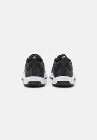 Black athletic shoes with a textured mesh upper, white midsole, flat black outsole, and rear pull tabs with "TRAINING" embossed.