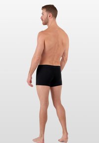 Černé pánské boxerky, bavlněný materiál, přiléhavý design, hladká textura a elastický pas. Zobrazeno z bočního úhlu.