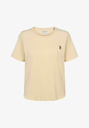 Kratke rukave, rebrasta rumena majica s okruglim izrezom i valovitim rubom. Ima mali vezeni logotip na lijevoj strani grudi.