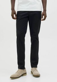 Zwarte katoenen broek in een slanke pasvorm, met een gladde textuur en zonder zichtbare patronen, gecombineerd met lichtbeige schoenen.