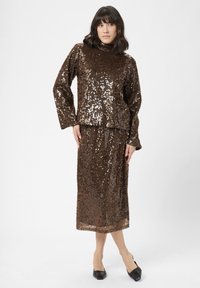 Bruin glinsterend twee-delig outfit met een hoog gesloten lange mouw top en een bijpassende knielange rok, met een gladde, glanzende textuur.