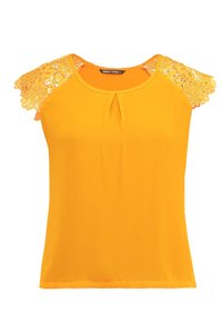 Top giallo a maniche corte con dettagli in pizzo sulle spalle, caratterizzato da uno scollo rotondo e una leggera piega sul davanti per un tocco in più.