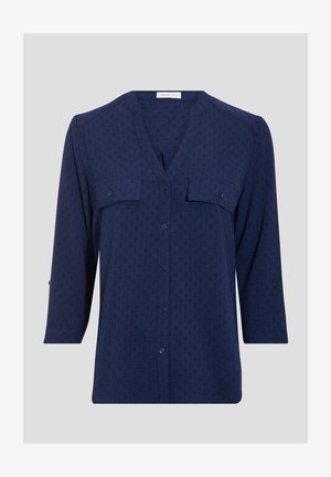 Navy blouse in lightweight fabric featuring a V-neck, two front pockets, three-quarter sleeves, and a subtle textured pattern.