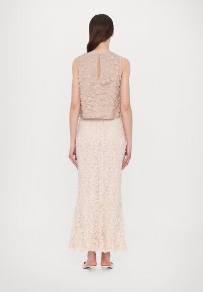 Lace dress in soft beige with floral embellishments on a fitted bodice and flare skirt. Features a keyhole back and smooth texture.