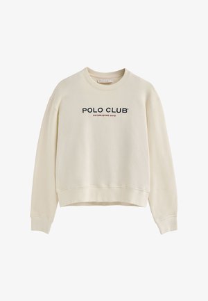 Sweatshirt légèrement beige avec un col rond, des manches longues et un design cropped ; comporte "POLO CLUB" et "ÉTABLI EN 2012" en texte bleu marine et rouge.