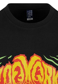 Sort bomulds t-shirt med fed, ildrød og gul grafisk tekst med grønne accenter. Rund halsudskæring, korte ærmer og almindelig pasform.