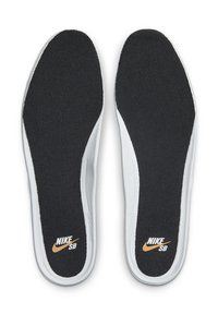 Mustat pehmustetut pohjalliset, joissa on teksturoidun pinnan valkoinen reuna, sisältävät kullanvärisen Nike SB -logon kantapäässä ja sivulla.