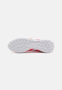 Red and white athletic shoe sole with textured rubber, featuring a distinct pattern and "PREDATOR" branding on the side.
