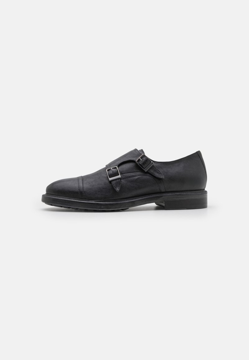 Chaussures en cuir noir avec un bout arrondi, des accents à double boucle et une finition texturée. Semelle plate avec un petit talon.
