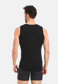 Black sleeveless top made of smooth fabric, featuring a rounded neckline and a slightly curved hem, paired with dark shorts.