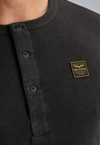 Tamno siva henley majica s rebrastim ovratnikom, tri crna dugmeta i logotip PME Legend sa zlatnim akcentom na lijevoj strani prsiju.