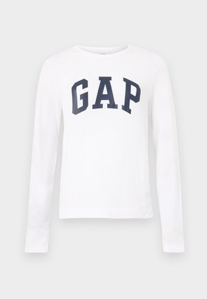 Chemise blanche à manches longues avec encolure ronde et "GAP" imprimé en grandes lettres bleu marine sur la poitrine.