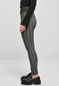Svarte leggings med et hundetannet mønster i grått, ribbet liv, tettsittende silhuett, kombinert med kraftige svarte sko.
