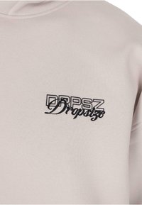 Jasnoszary sweatshirt z podwójnym kapturem, kieszenią z przodu oraz czarnym haftowanym logo "DRPSZ Dropsize" na piersi.