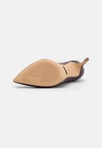 Rodo ašmenimis su tekstūruota violetinė medžiaga viršuje, lygiu bežiniu guminiu padu ir subtiliu ženklinimu apačioje. Slingback dizainas.