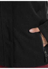 Schwarze Jacke mit einer Reißverschlusstasche und weichem Stoff. Das Design umfasst eine glatte Textur und einen geraden Schnitt mit minimalen Akzenten.