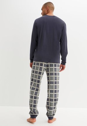 Haut à manches longues bleu marine avec un pantalon de pyjama gris à motif à carreaux. Les pantalons ont des poignets élastiques et une coupe confortable.