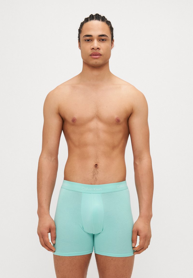 Boxeri scurți de culoare verde mentă, cu o textură netedă, având un logo Calvin Klein pe brâu și un design care se potrivește perfect.