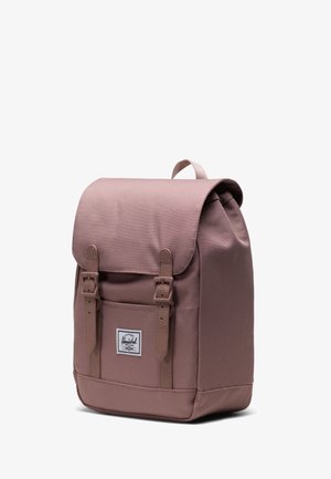 Ružičasti platneni ruksak s preklopnim poklopcem, dva podesiva remena, oznakom s logom i zaobljenom bazom za dodatnu čvrstoću.