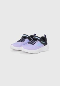 Baskets de sport violettes avec une tige en mesh, des accents noirs et une semelle en caoutchouc blanche. Présente une sangle avec un logo et des lacets contrastés.