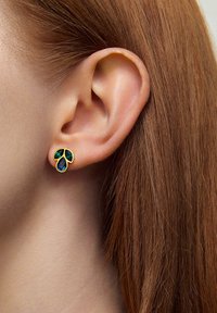 Złote kolczyki mają kwiatowy wzór z trzema akcentami gemów: dwoma zielonymi i jednym niebieskim, osadzonymi w kształcie kropli wody.